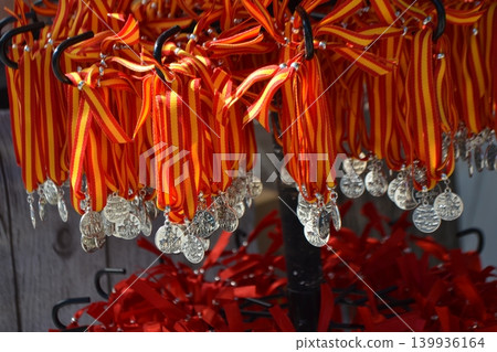 Striped red and yellow ribbon medals from san isidro fair hanging on display for market souvenir stall and festival background 139936164