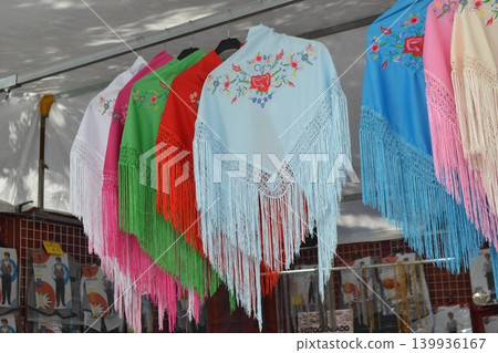 Embroidered fringed shawls in bright colors for feria san isidro madrid market stall display and flamenco costume background Embroidered fringed shawls in bright colors for feria san isidro madrid market stall display and flamenco costume background 139936167
