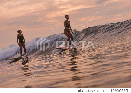 Dynamic Surfing Scene With Women And Companions In Evening Glow Dynamic Surfing Scene With Women And Companions In Evening Glow 139936885