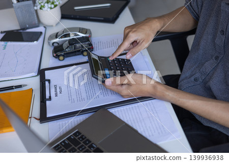Businessman Reviewing Insurance Policy and Calculating Vehicle Expenses, Monthly Installments, Tax or Insurance Payment. Businessman Reviewing Insurance Policy and Calculating Vehicle Expenses, Monthly Installments, Tax or Insurance Payment. 139936938