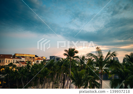 Palm trees and colorful resort architecture at dusk. A tropical townscape and a beautiful gradient of sky. Palm trees and colorful resort architecture at dusk. A tropical townscape and a beautiful gradient of sky. 139937218