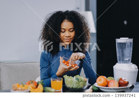 Young nutritionist showing bell peppers during an online video call consulting about healthy eating, sitting at home at a table with vegetables, laptop and measuring tape Young nutritionist showing bell peppers during an online video call consulting about healthy eating, sitting at home at a table with vegetables, laptop and measuring tape 139937241