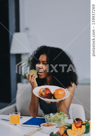 Young nutritionist showing bell peppers during an online video call consulting about healthy eating, sitting at home at a table with vegetables, laptop and measuring tape Young nutritionist showing bell peppers during an online video call consulting about healthy eating, sitting at home at a table with vegetables, laptop and measuring tape 139937269