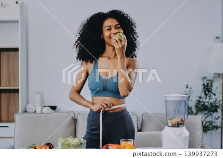 Young nutritionist showing bell peppers during an online video call consulting about healthy eating, sitting at home at a table with vegetables, laptop and measuring tape Young nutritionist showing bell peppers during an online video call consulting about healthy eating, sitting at home at a table with vegetables, laptop and measuring tape 139937273