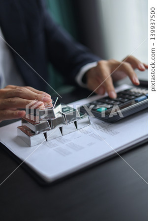 Silver Bullion Investment and Financial Analysis. Businessman Calculating Investment Returns with Silver Bars and Financial Documents. Silver Bullion Investment and Financial Analysis. Businessman Calculating Investment Returns with Silver Bars and Financial Documents. 139937500