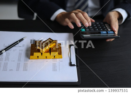 Gold investment concept. Businessman working on financial planning and gold investment analysis with bullion and calculator. 139937531