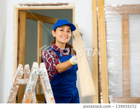 Cheerful female repairer carrying bunch of wooden planks 139938252