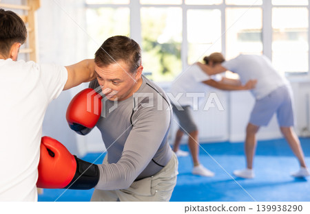 Man with guy practicing boxing body blow in sport club Man with guy practicing boxing body blow in sport club 139938290