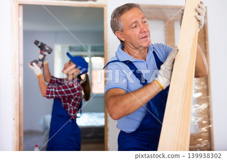 Man builder carrying wooden planks in construction site Man builder carrying wooden planks in construction site 139938302