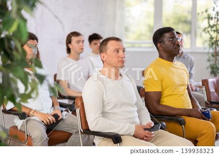 Adult man listening to lecture in auditorium with male students Adult man listening to lecture in auditorium with male students 139938323
