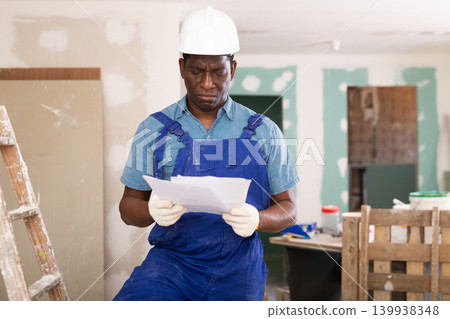 African american foreman examines documents and plans a workflow for repairs 139938348