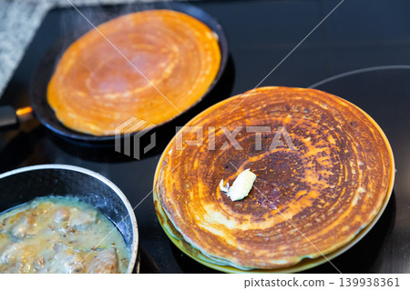 Frying pancakes in frying pan in kitchen Frying pancakes in frying pan in kitchen 139938361