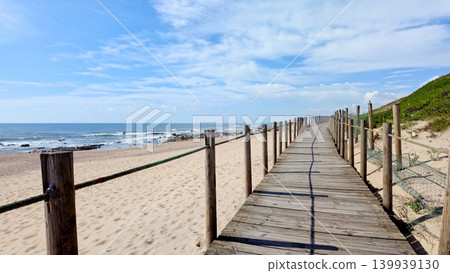 Wooden Boardwalk Leading Along the Sandy Coastline of Miramar Beach in Portugal Wooden Boardwalk Leading Along the Sandy Coastline of Miramar Beach in Portugal 139939130