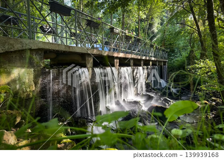 Small waterfall and pedestrian bridge with flower pots at Parque de Lazer da Varzea in Santa Maria da Feira Portugal Small waterfall and pedestrian bridge with flower pots at Parque de Lazer da Varzea in Santa Maria da Feira Portugal 139939168