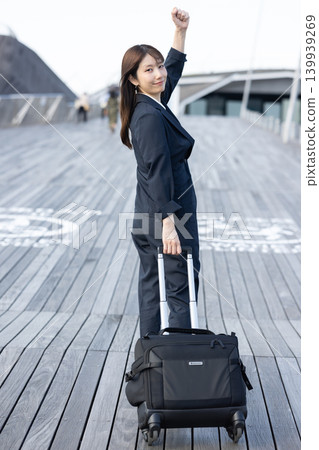一位女商人拖著行李箱準備出差。 139939269
