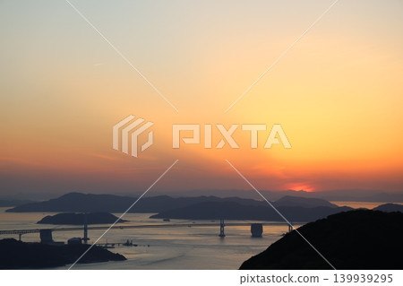 The Seto Ohashi Bridge at dusk and the sunset sky and sun sinking into the Seto Inland Sea 4 The Seto Ohashi Bridge at dusk and the sunset sky and sun sinking into the Seto Inland Sea 4 139939295