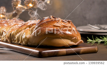 Homemade braided sweet Christmas bread with sliced almonds on a wooden board Homemade braided sweet Christmas bread with sliced almonds on a wooden board 139939562