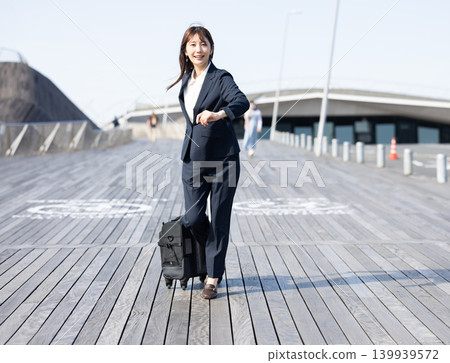 一位女商人拖著行李箱準備出差。 139939572