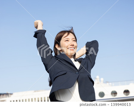 A woman in a suit is overjoyed and makes a victory pose. 139940013