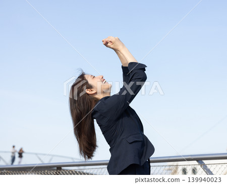 A woman in a suit is overjoyed and makes a victory pose. A woman in a suit is overjoyed and makes a victory pose. 139940023