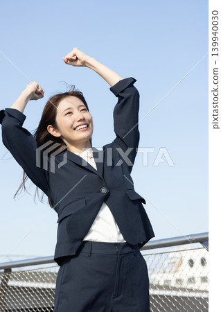 A woman in a suit is overjoyed and makes a victory pose. A woman in a suit is overjoyed and makes a victory pose. 139940030