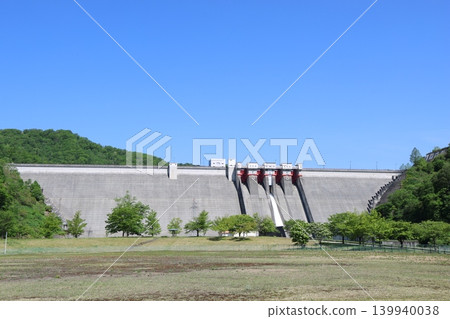 A panoramic view of the magnificent Tamagawa Dam in Tamagawa, Akita Prefecture, under a blue sky, and the water being released. A panoramic view of the magnificent Tamagawa Dam in Tamagawa, Akita Prefecture, under a blue sky, and the water being released. 139940038
