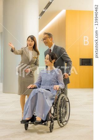 Staff member guiding a middle-aged couple to the event hall. 139940462