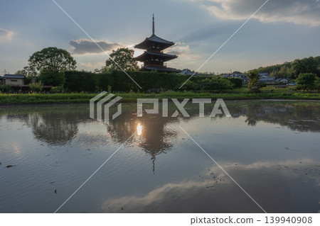 A photograph of the warming rice paddies reflecting Hokiji Temple, a scene from early summer in Ikaruga. A photograph of the warming rice paddies reflecting Hokiji Temple, a scene from early summer in Ikaruga. 139940908