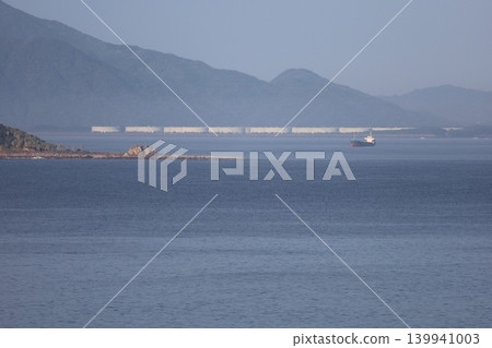 Under a clear blue sky, islands and ships can be seen beyond the breakwater. Under a clear blue sky, islands and ships can be seen beyond the breakwater. 139941003