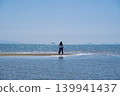 A woman with her back to the camera stands at the tip of the sandbar at Chichibugahama beach, with the sparkling Seto Inland Sea in front of her (Kagawa Prefecture). 139941437