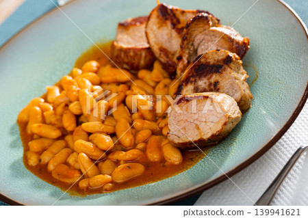 Delicious meat dish of roast pork and stewed beans on blue plate Delicious meat dish of roast pork and stewed beans on blue plate 139941621