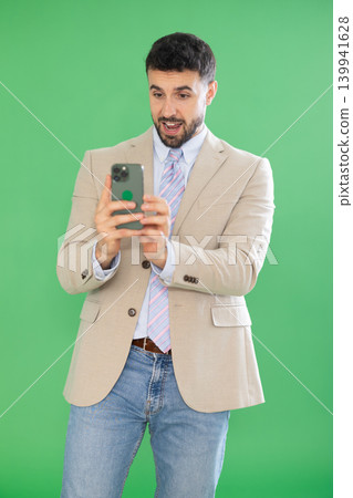 Adult man taking photo or scanning QR code in front of green screen Adult man taking photo or scanning QR code in front of green screen 139941628