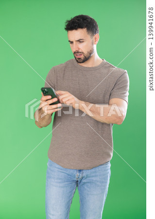 Adult man scrolling smartphone screen in front of green screen 139941678