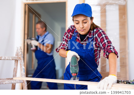 Woman carpenter using jigsaw in construction site Woman carpenter using jigsaw in construction site 139941703