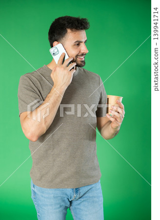 Man with cup of coffee is talking on phone, emotionally communicating with friend Man with cup of coffee is talking on phone, emotionally communicating with friend 139941714