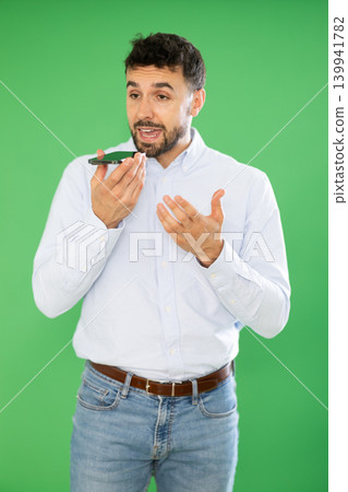Adult man emotionally records an audio message on a mobile phone. Chroma key compositing Adult man emotionally records an audio message on a mobile phone. Chroma key compositing 139941782