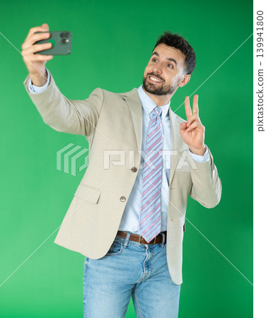 Happy adult man takes selfie on a green background. Chroma key compositing Happy adult man takes selfie on a green background. Chroma key compositing 139941800