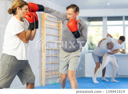 Men in boxing gloves punch deliver blow each other during training sparring session. Men in boxing gloves punch deliver blow each other during training sparring session. 139941814