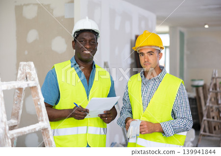 Portrait of positive men builders inside apartment during repair works Portrait of positive men builders inside apartment during repair works 139941844