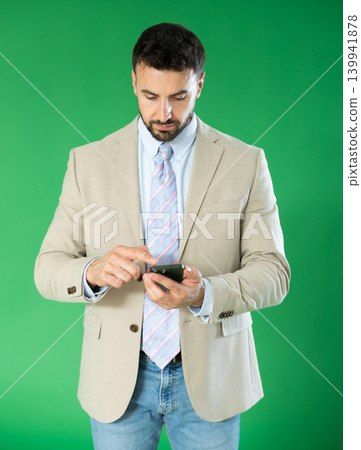 Adult man scrolling smartphone screen in front of green screen Adult man scrolling smartphone screen in front of green screen 139941878