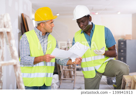 Engineer and architect talking about documents in construction site Engineer and architect talking about documents in construction site 139941913