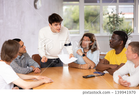 Guy student discussing assignments with male group around table Guy student discussing assignments with male group around table 139941970