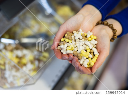 Handful of nutritious bone shaped dog snacks in female hands Handful of nutritious bone shaped dog snacks in female hands 139942014