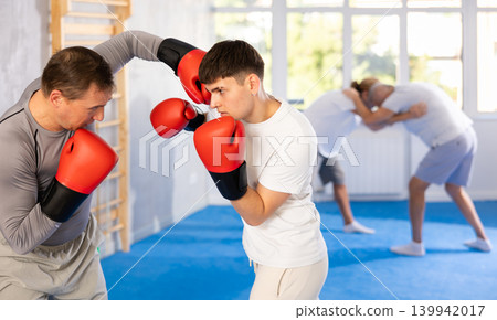 Portrait of defferent ages active sportsmen competing in boxing gloves Portrait of defferent ages active sportsmen competing in boxing gloves 139942017