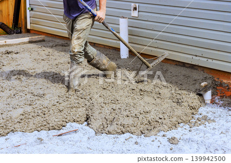 Worker uses level tool to smooth out wet concrete at home construction site Worker uses level tool to smooth out wet concrete at home construction site 139942500
