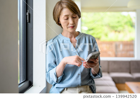 A woman who manipulates a smartphone at the window side A woman who manipulates a smartphone at the window side 139942520