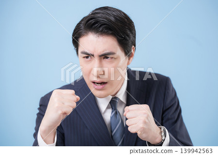 一位身穿西裝的商人揮舞著拳頭,展現他的勝利、成功以及為挑戰而戰的精神。 一位身穿西裝的商人揮舞著拳頭,展現他的勝利、成功以及為挑戰而戰的精神。 139942563