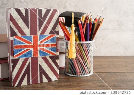 UK flag with graduate hat on english language book. UK flag with graduate hat on english language book. 139942725