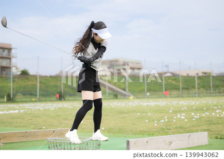 一張年輕女高爾夫球手在練習場揮桿的運動照片。 一張年輕女高爾夫球手在練習場揮桿的運動照片。 139943062