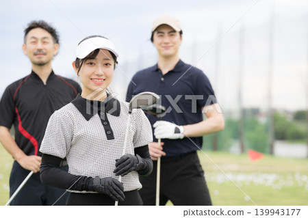 一位女士微笑著學習打高爾夫球;與她的高爾夫教練和朋友們一起享受健康的生活方式;她的笑容直視著鏡頭。 一位女士微笑著學習打高爾夫球;與她的高爾夫教練和朋友們一起享受健康的生活方式;她的笑容直視著鏡頭。 139943177
